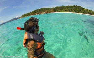 A woman enjoying her first solo trip snorkling in the clear blue water.