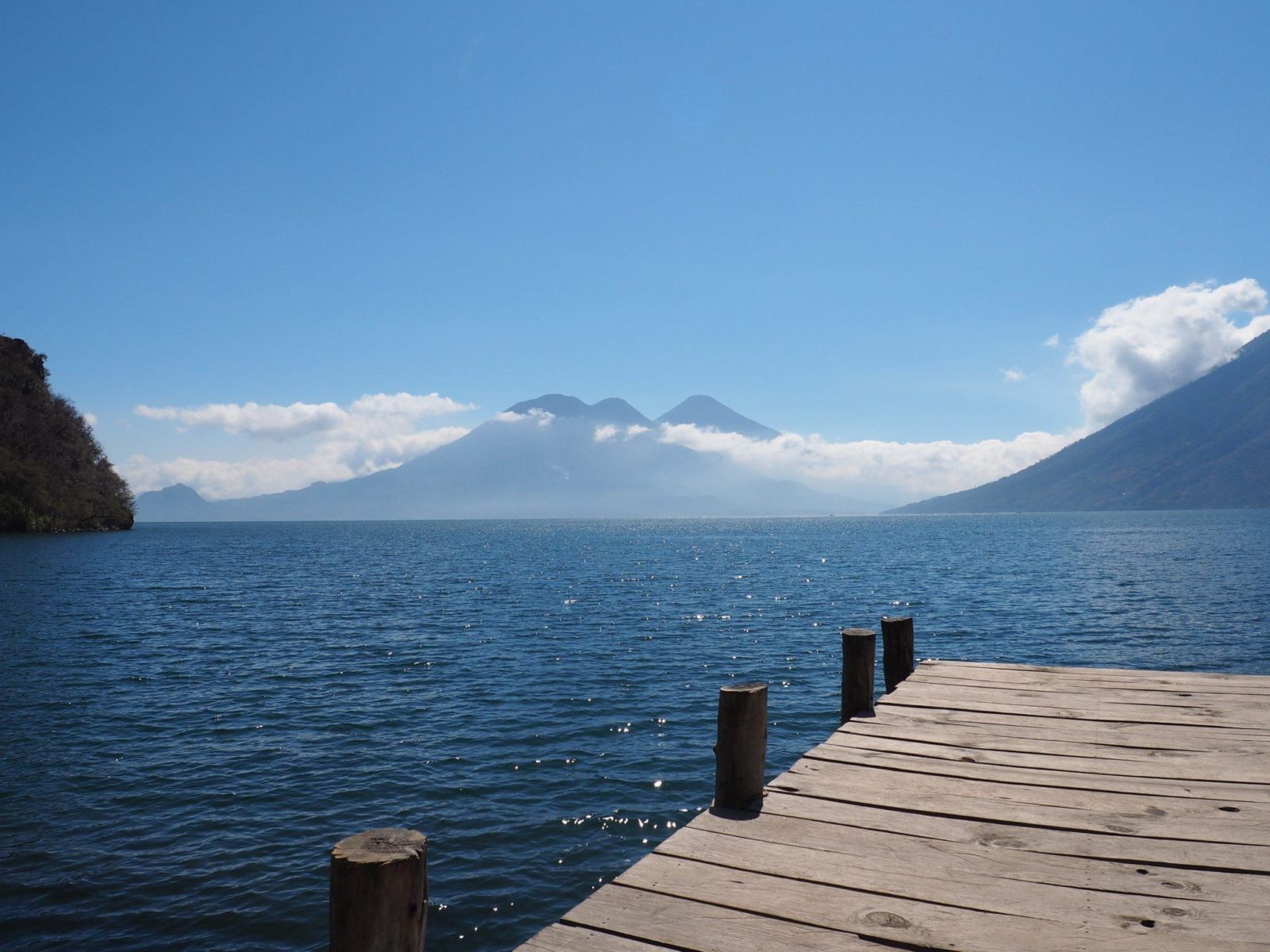 A wooden dock on Lake Atitlan with mountains in the background.