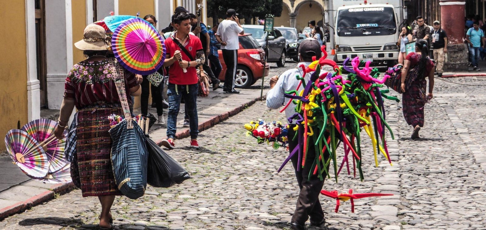 4 days in Antigua: A group of people walking down a cobblestone street with colorful umbrellas.