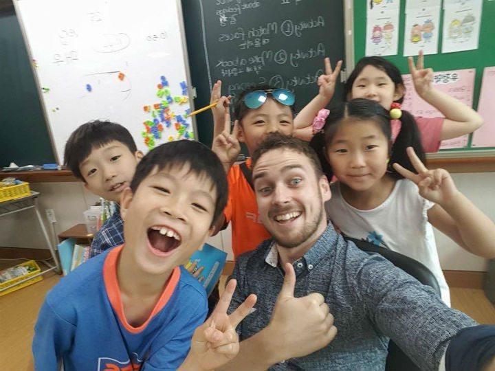 A group of children posing for a photo in a South Korean classroom while learning English.