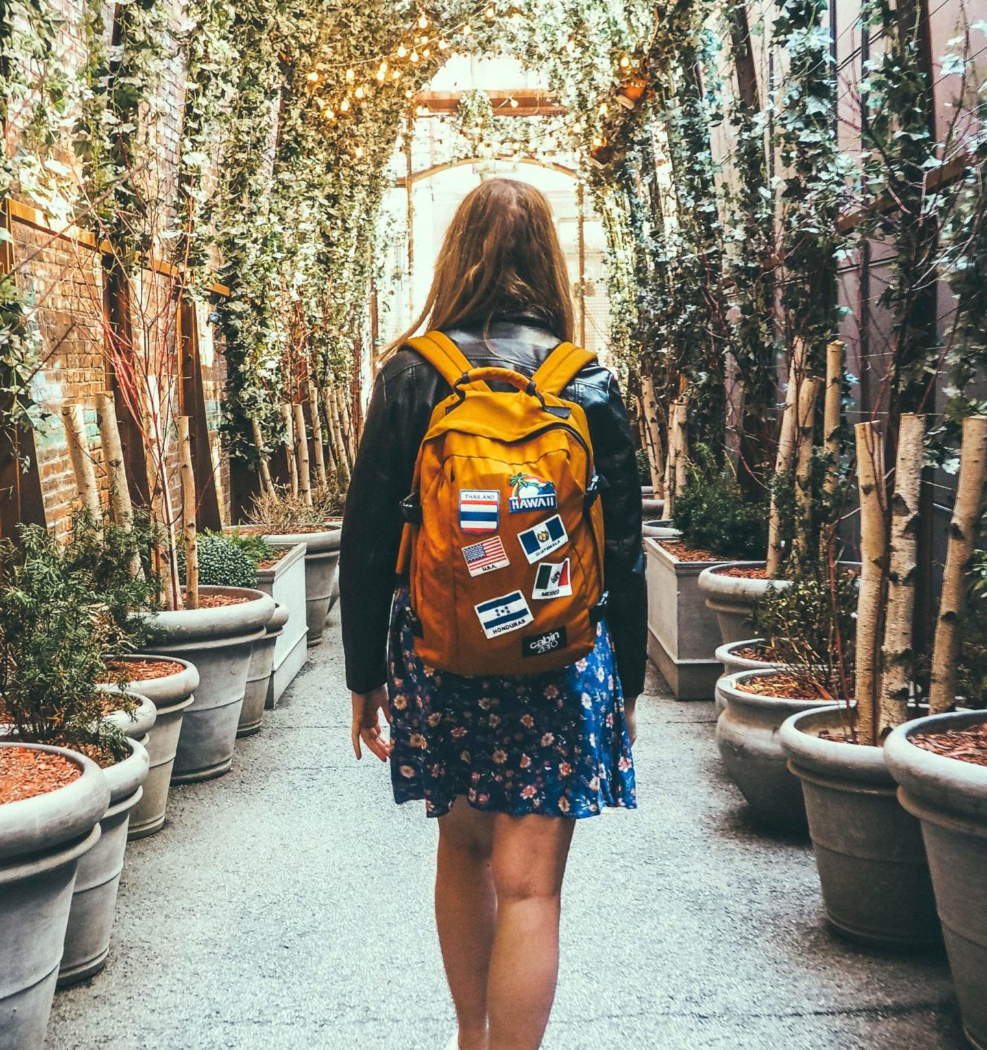 A woman walking down an alleyway with a backpack, on her way to work with Claire's Itchy Feet.