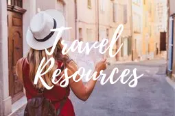 A woman in a red dress walking down a street with travel resources.