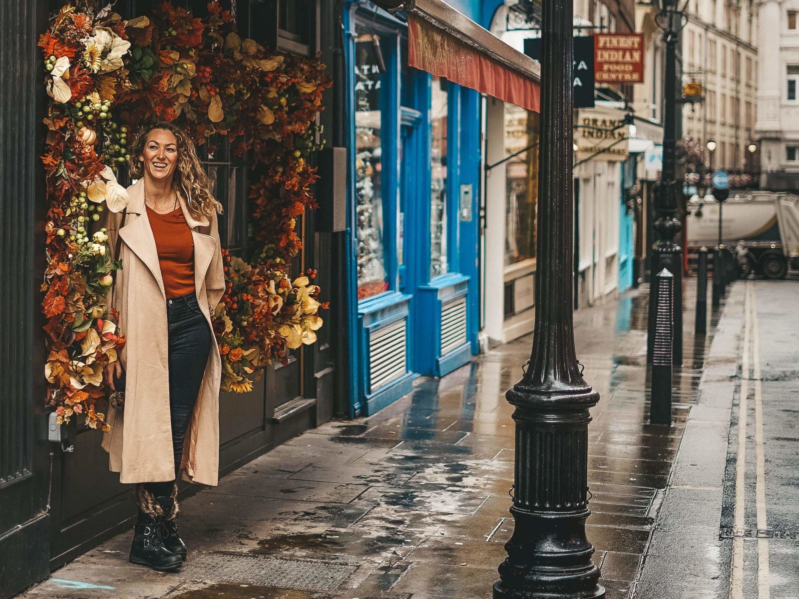 A woman standing on a rainy street in London, capturing one of the beautiful Instagram spots in the city.