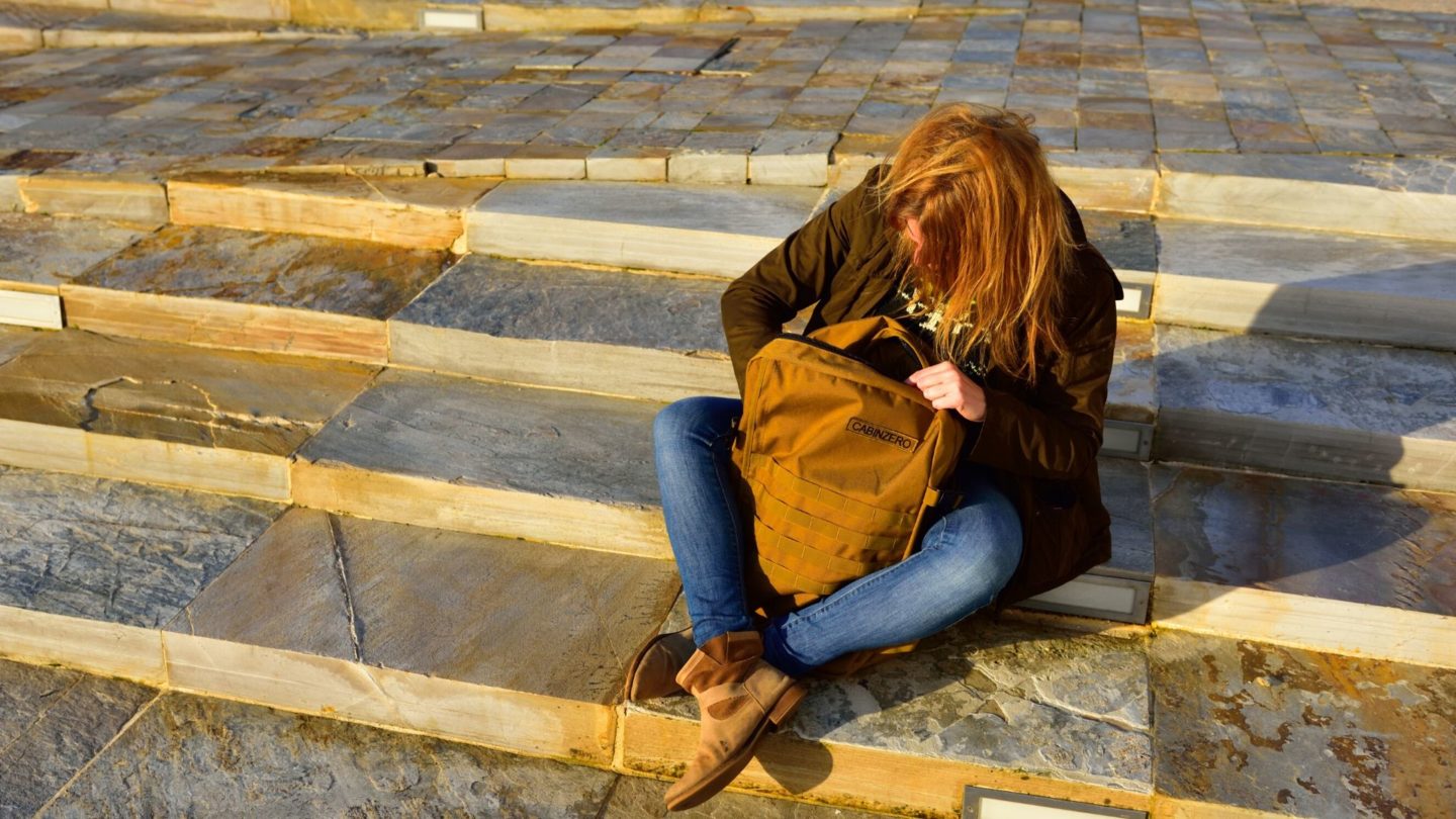 A woman with a Nomad Backpack sitting on steps.