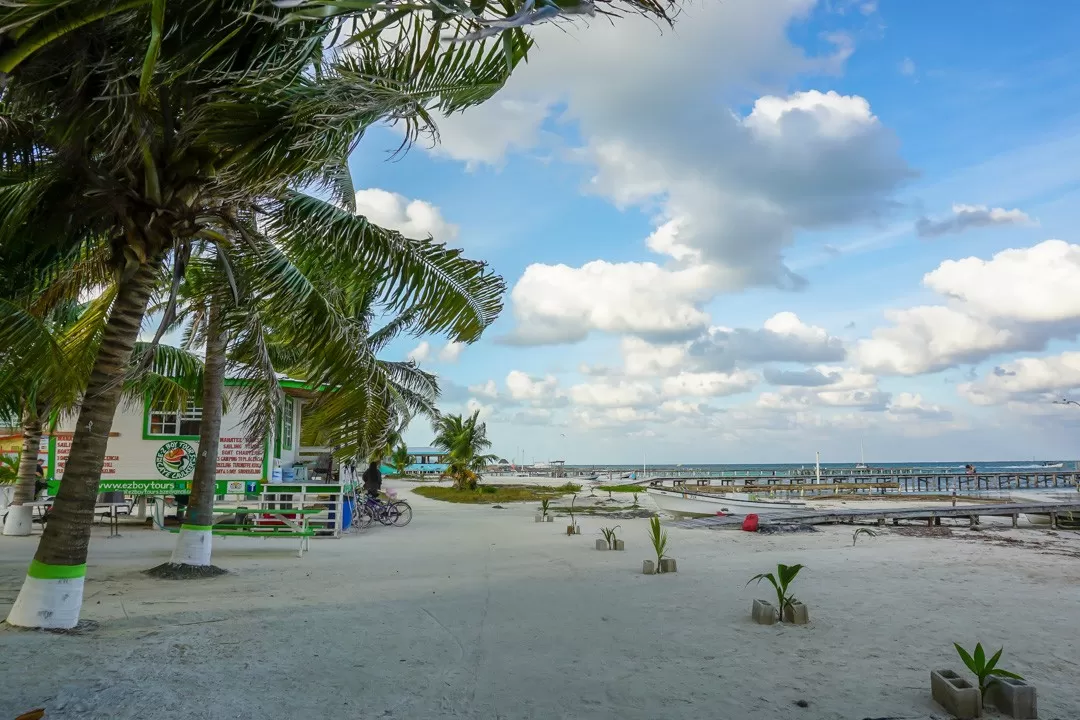 A tropical beach in Belize with palm trees and a restaurant, perfect for your safe vacation in Belize.