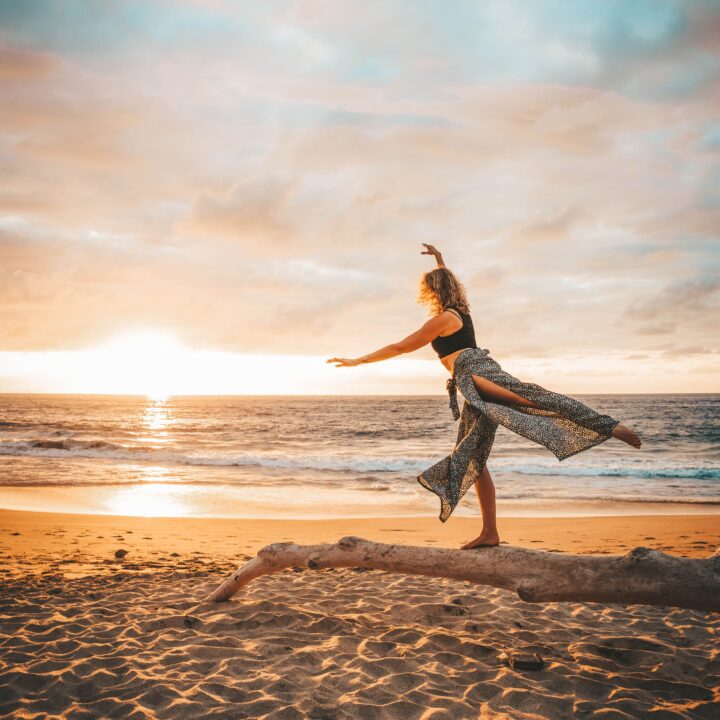 A woman practicing yoga on the beach during a mesmerizing sunset, perfect for capturing stunning travel photography.