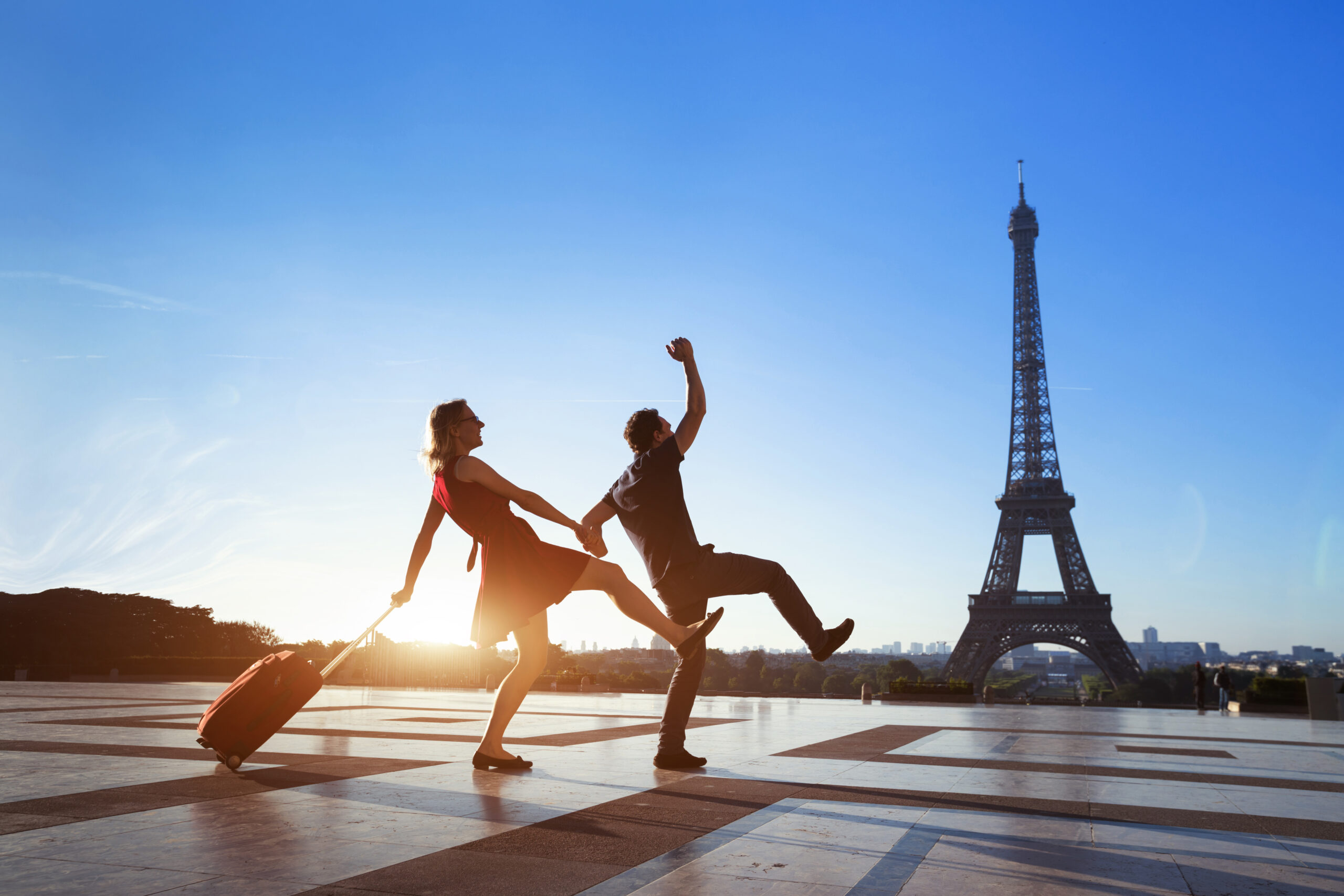 Two people traveling from London to Paris, dancing in front of the Eiffel Tower while waiting for their train.