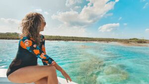 A woman in a swimsuit enjoying the scenic beauty of Bacalar, Mexico from the back of a boat.