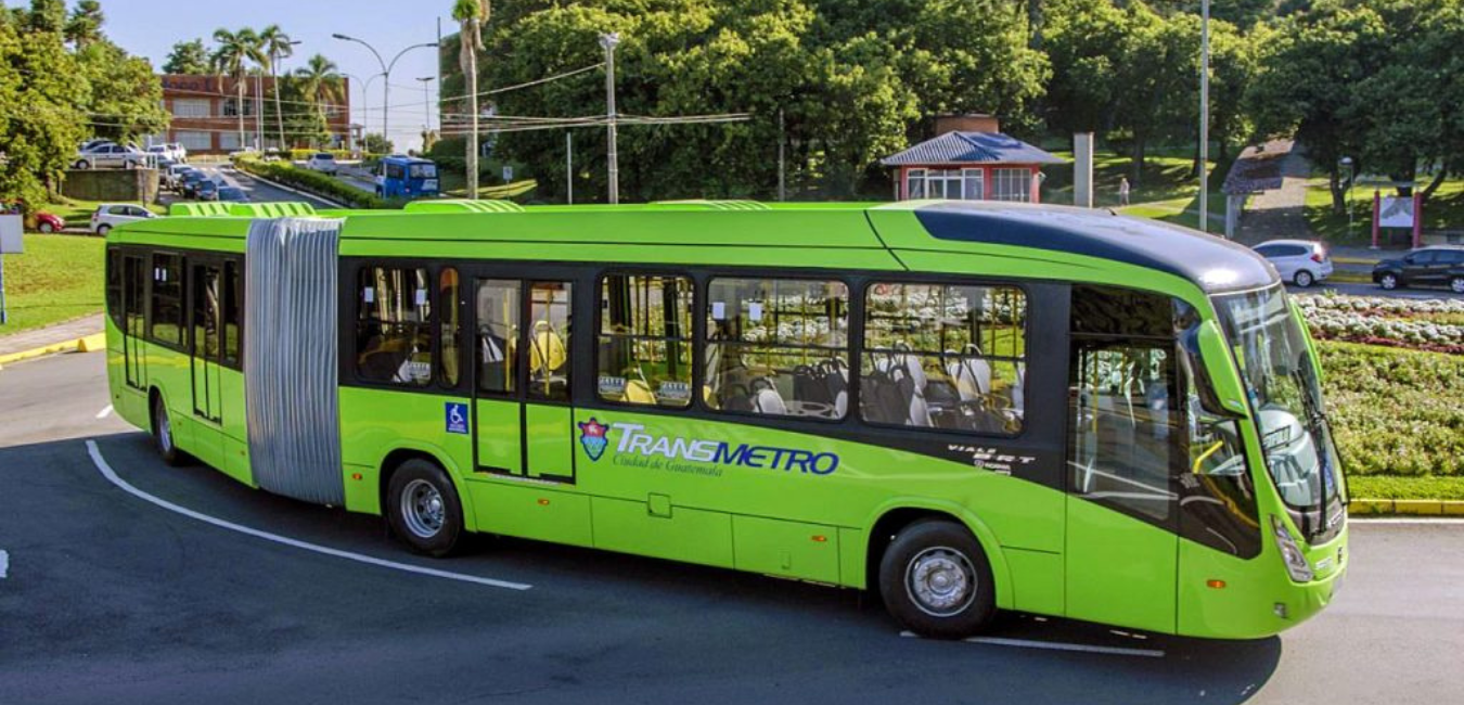 A green bus is driving down the streets of Guatemala City.