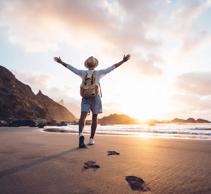 A man standing on the beach with his arms outstretched.