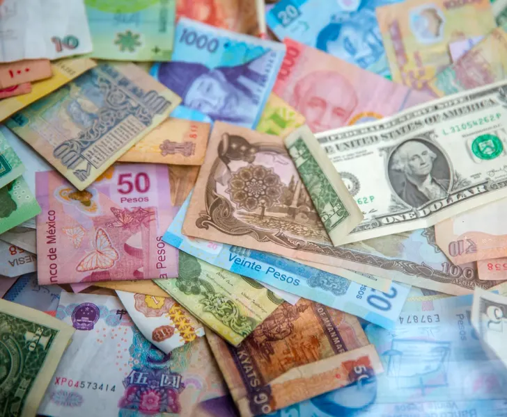 Many different types of currency from various countries are laying on top of each other.