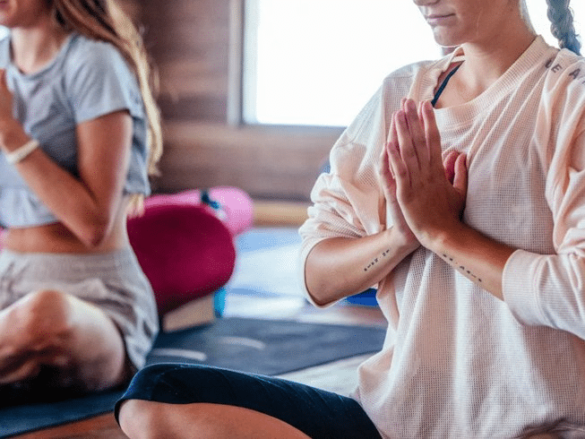 Two women practicing yoga in a yoga studio during an online yoga teacher training.