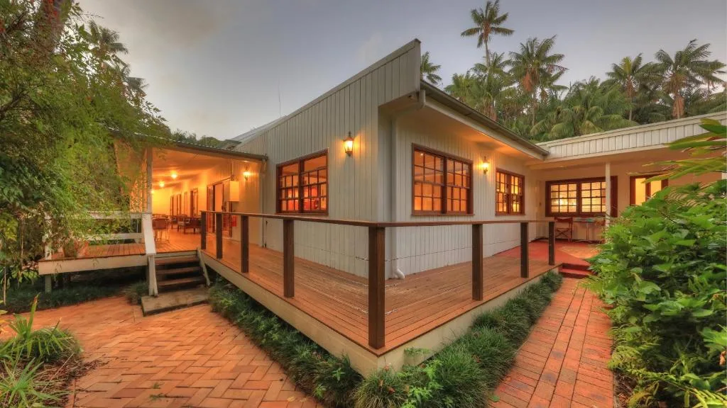 Tropical house exterior at dusk with lit windows
