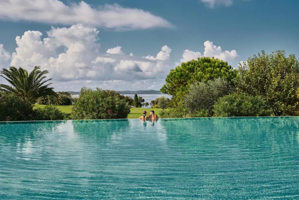 People swimming in an infinity pool surrounded by greenery