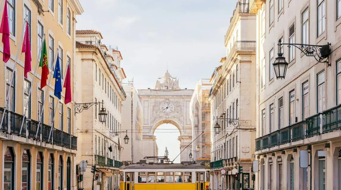 Historic Lisbon street with tram and archway in sunlight