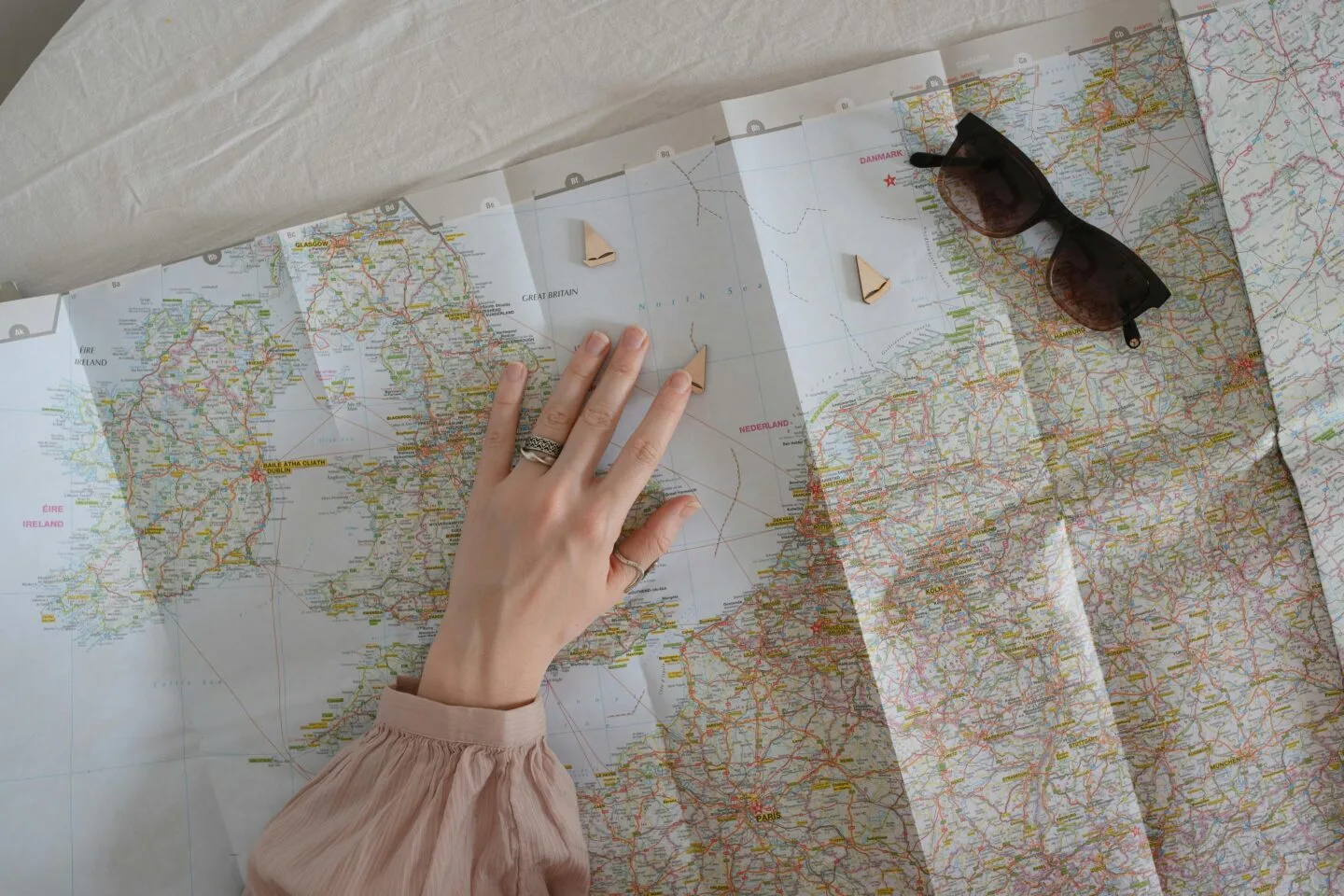 Hand pointing on a map with sunglasses beside.