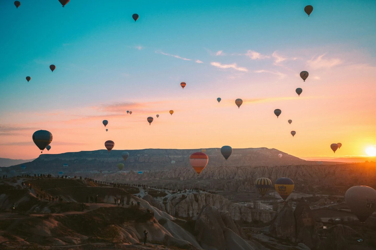 Sunrise with hot air balloons over rocky landscape