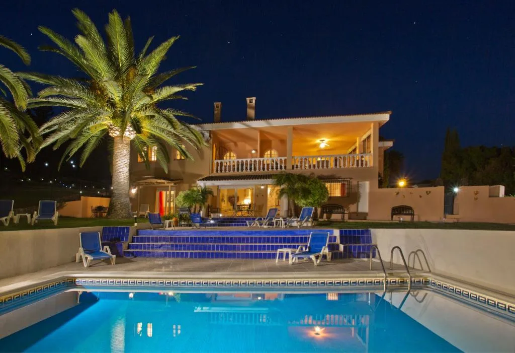 Luxury villa with pool and palm trees at night