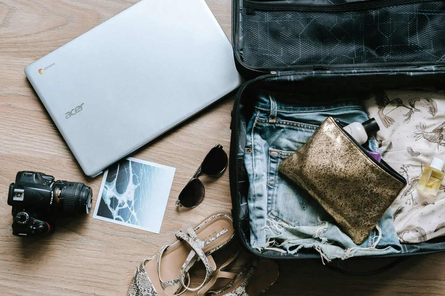 Open suitcase with laptop, camera, and travel essentials