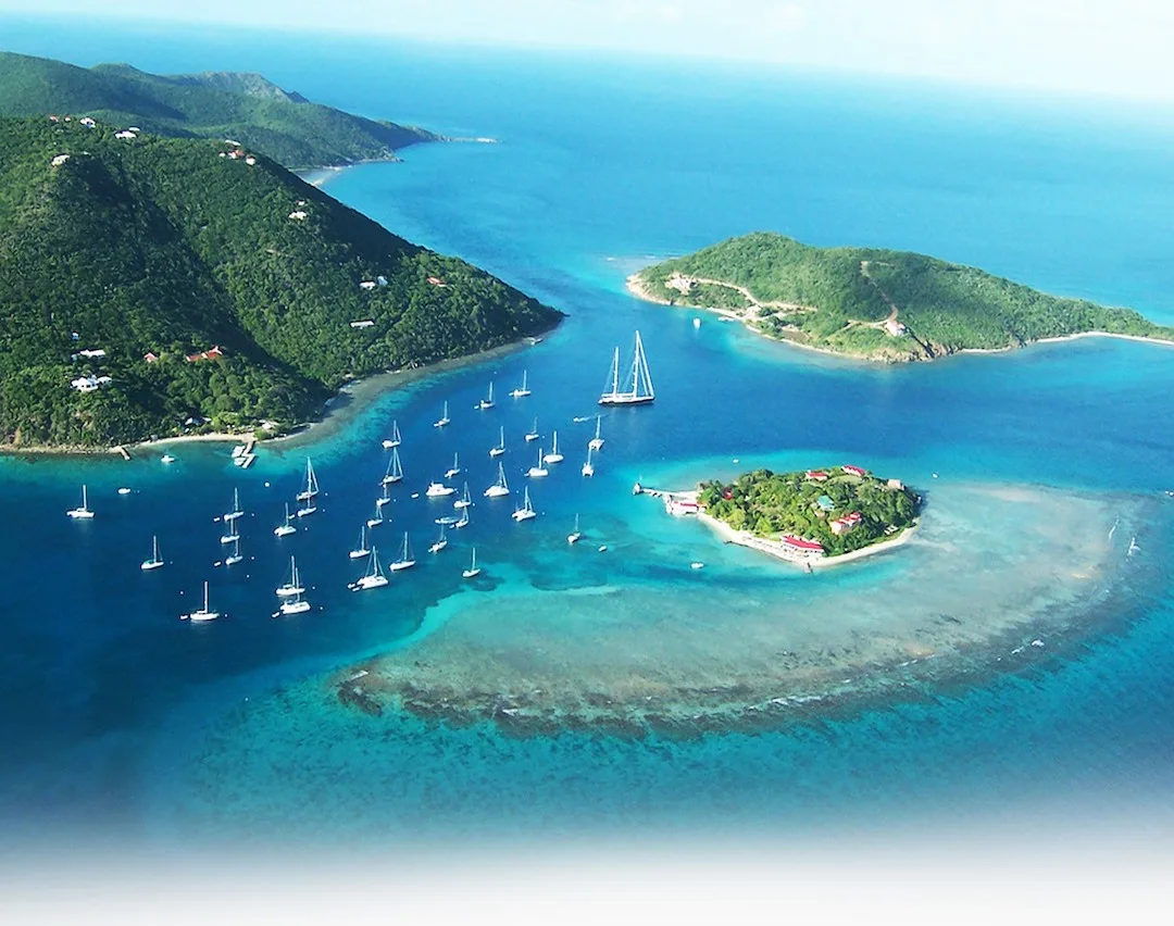 Aerial view of lush island with boats and clear waters