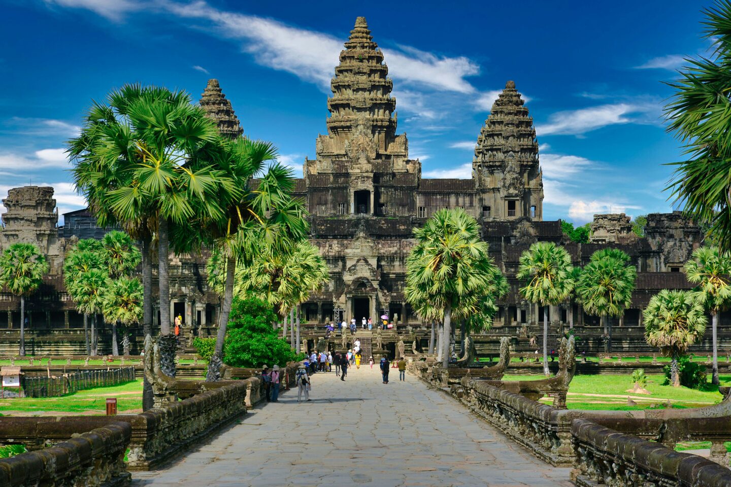 Angkor Wat temple with tourists and lush palms