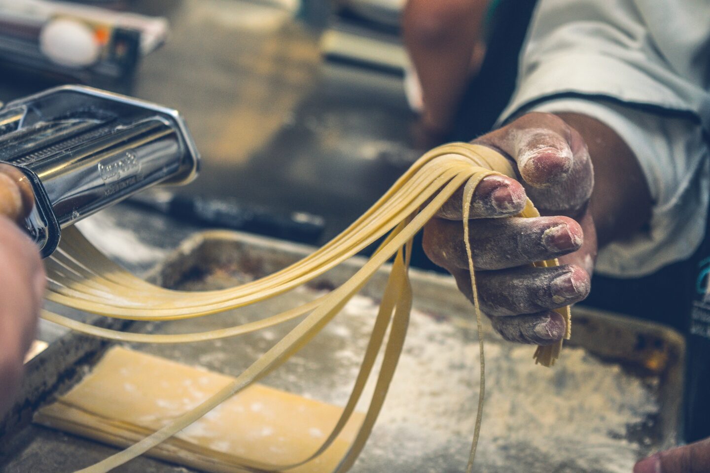 Close-up of hands making fresh pasta with machine