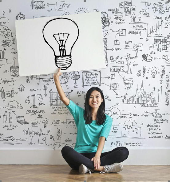 Woman holding up lightbulb drawing in creative workspace