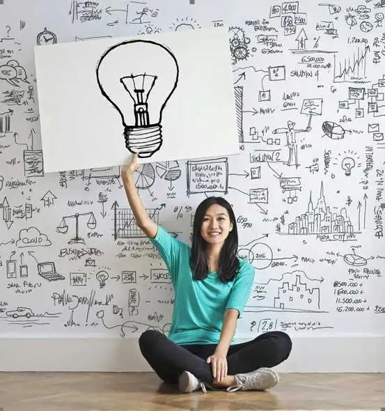 Woman holding up lightbulb drawing in creative workspace