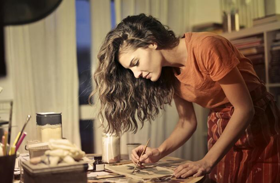 Woman intently painting in a cozy home studio