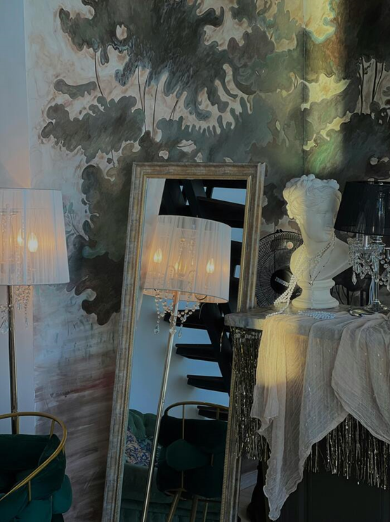 Elegant interior with mirrored wall, artistic bust, and lamps