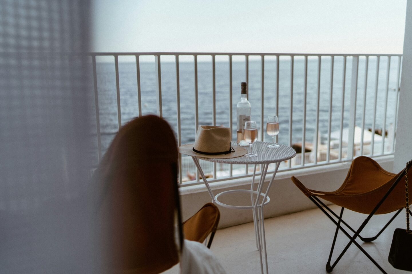 Seaside balcony with wine, glasses, and a hat