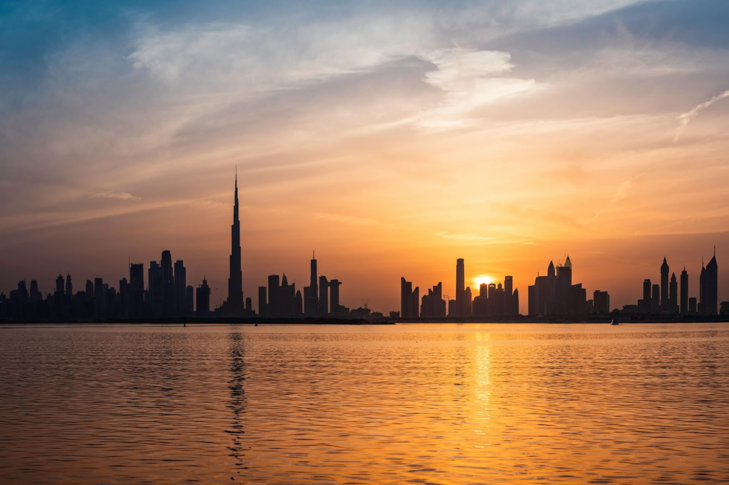 Sunset silhouette of Dubai skyline over water