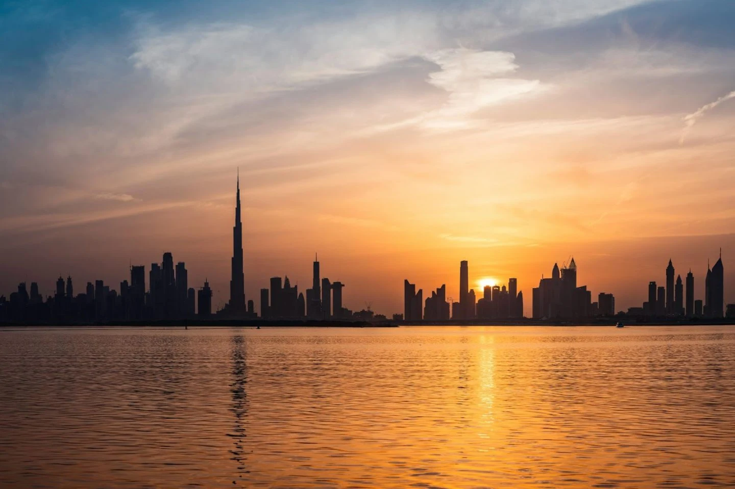 Sunset silhouette of Dubai skyline over water