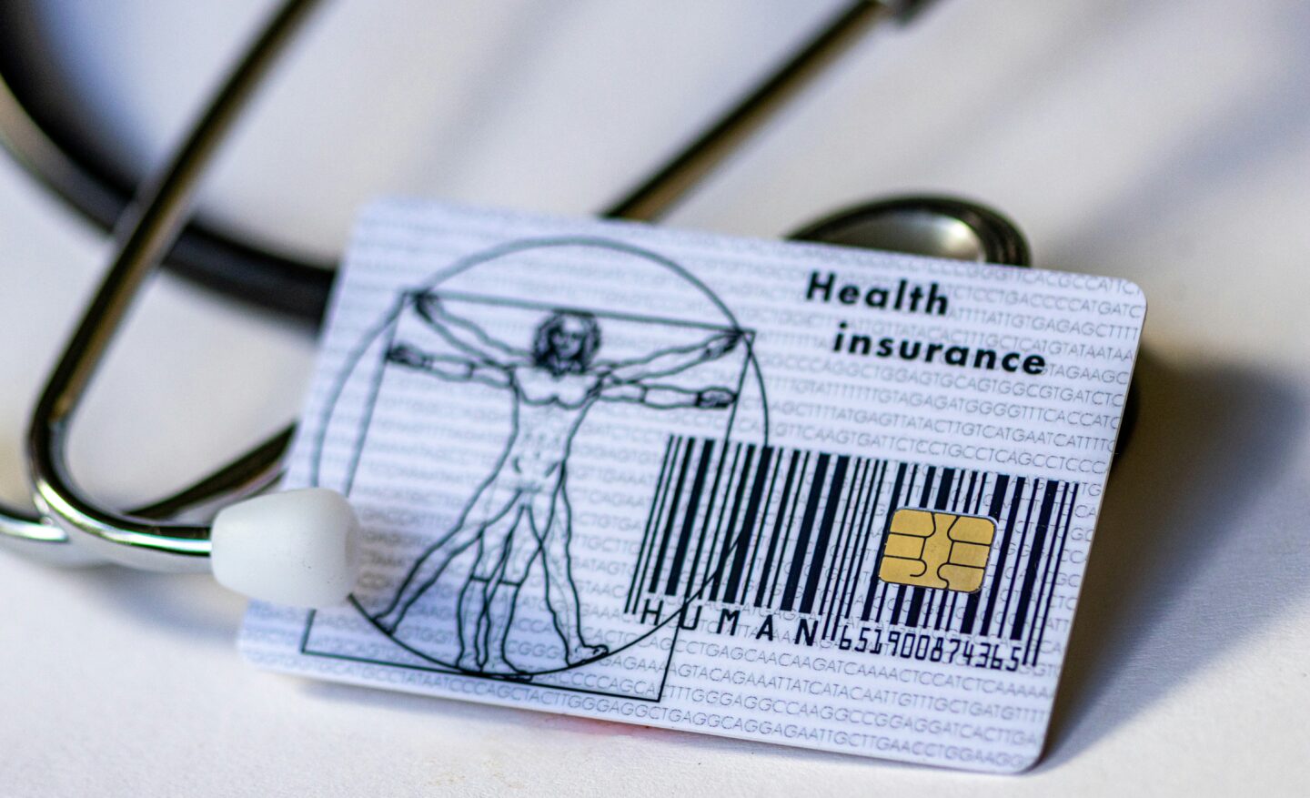Health insurance card with stethoscope on white surface