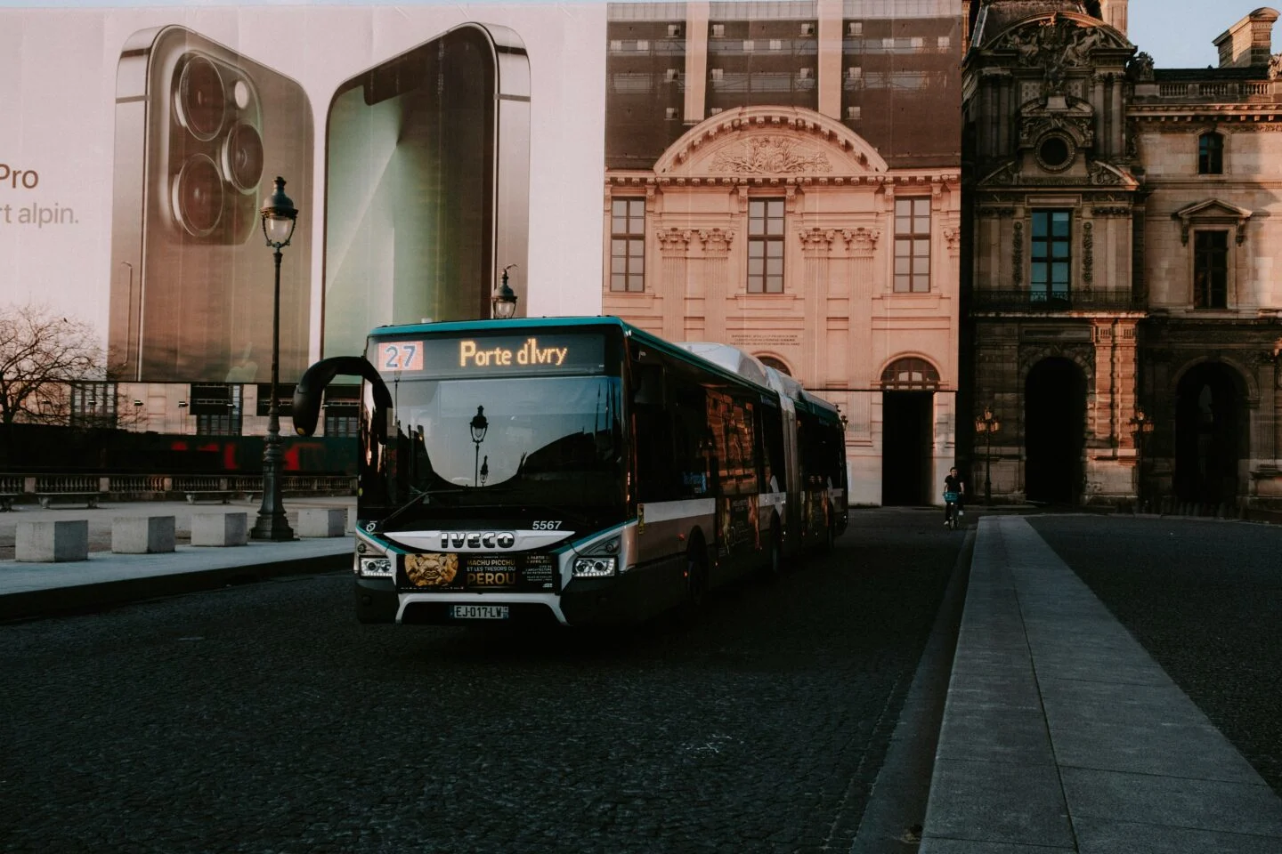 City bus near historic building with large phone ad