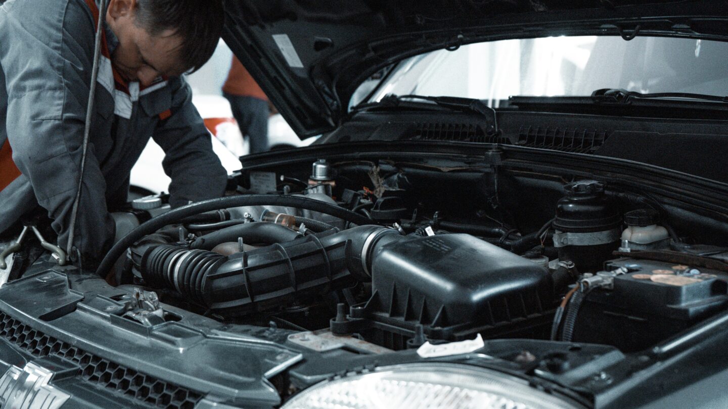 Mechanic repairing car engine in workshop