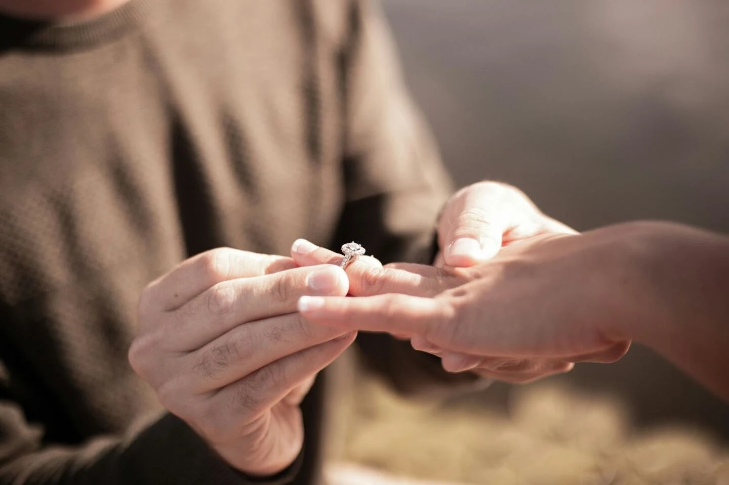 Close-up of engagement ring exchange between two hands