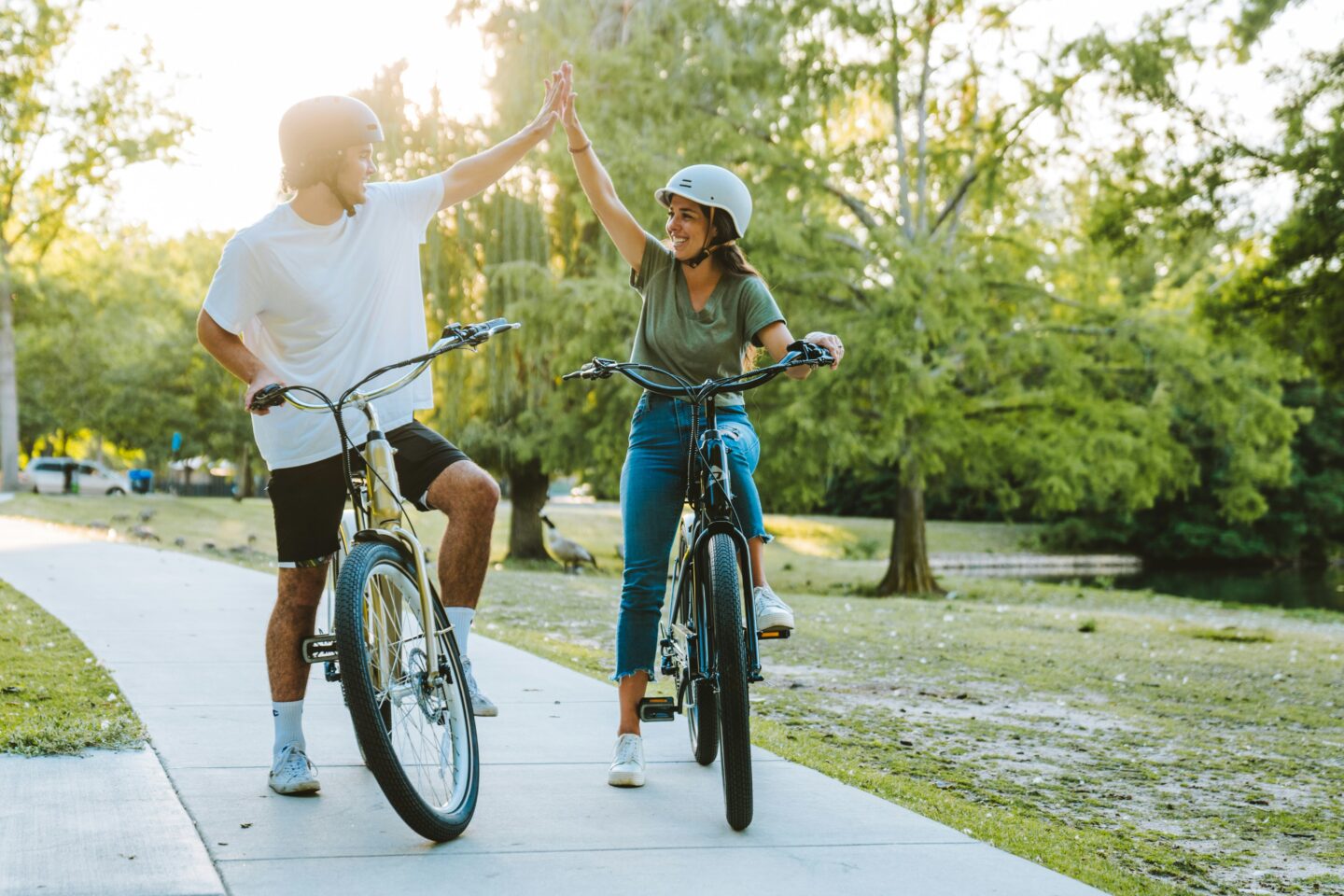 Two people high-fiving while biking in park
