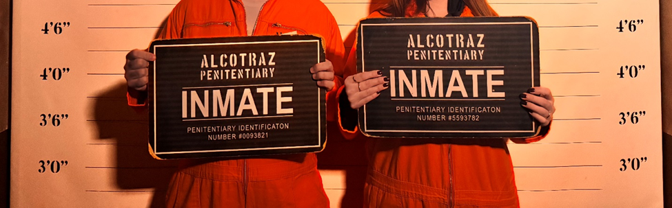 Two people holding Alcatraz inmate identification signs