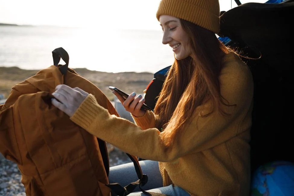 Woman in beanie using smartphone by lakeside