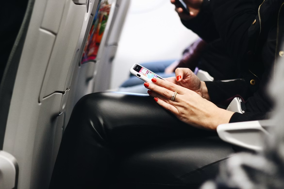 Person using smartphone on airplane seat