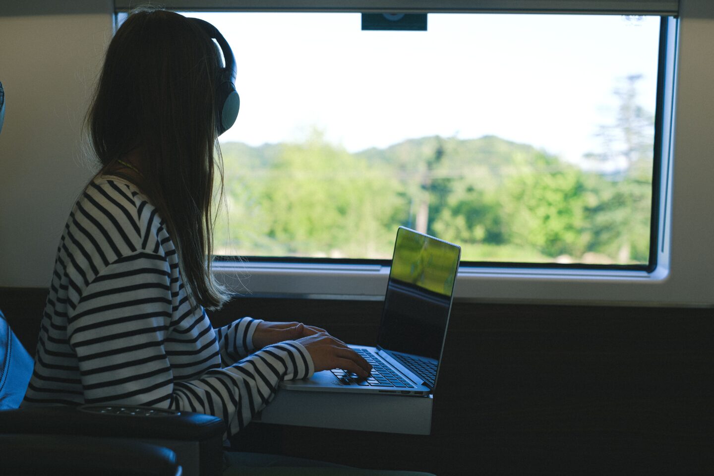 Woman working on laptop in train with scenic view