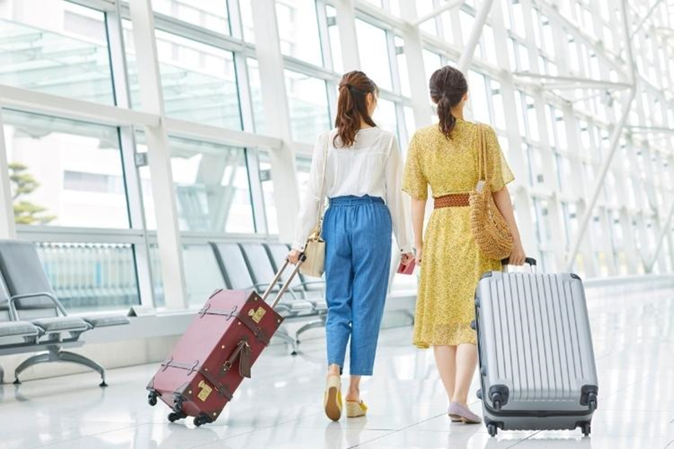 Two women walking with luggage in airport terminal