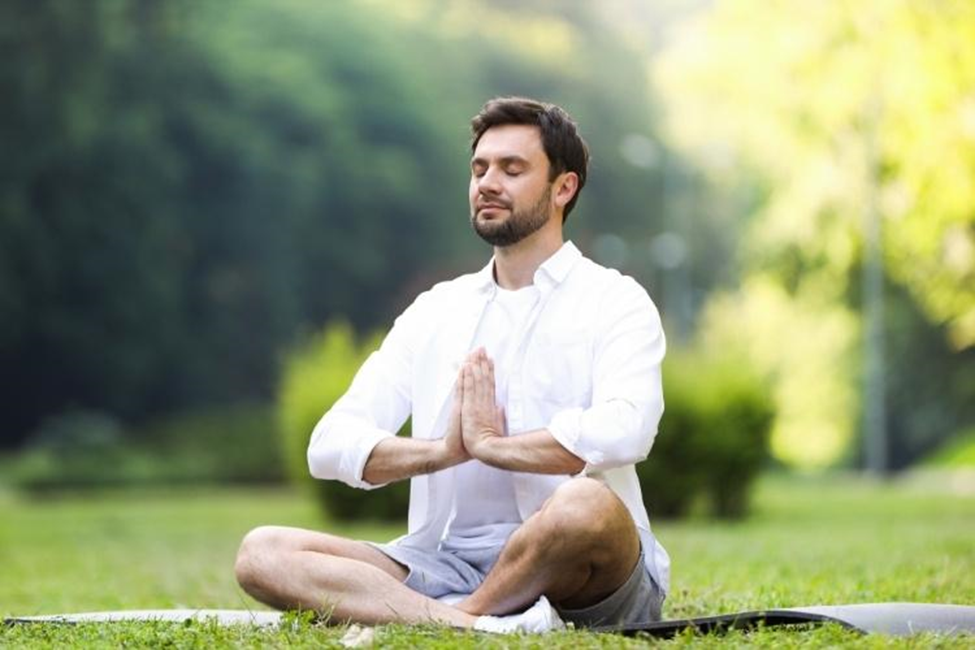 Man meditating peacefully in sunny park