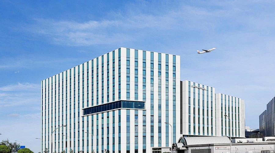 Modern striped building under blue sky with flying airplane